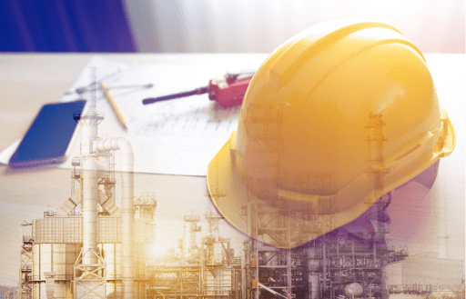 Yellow hard hat on a desk with industrial plant overlay